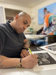 Photo of a man holding a pencil and signing a print